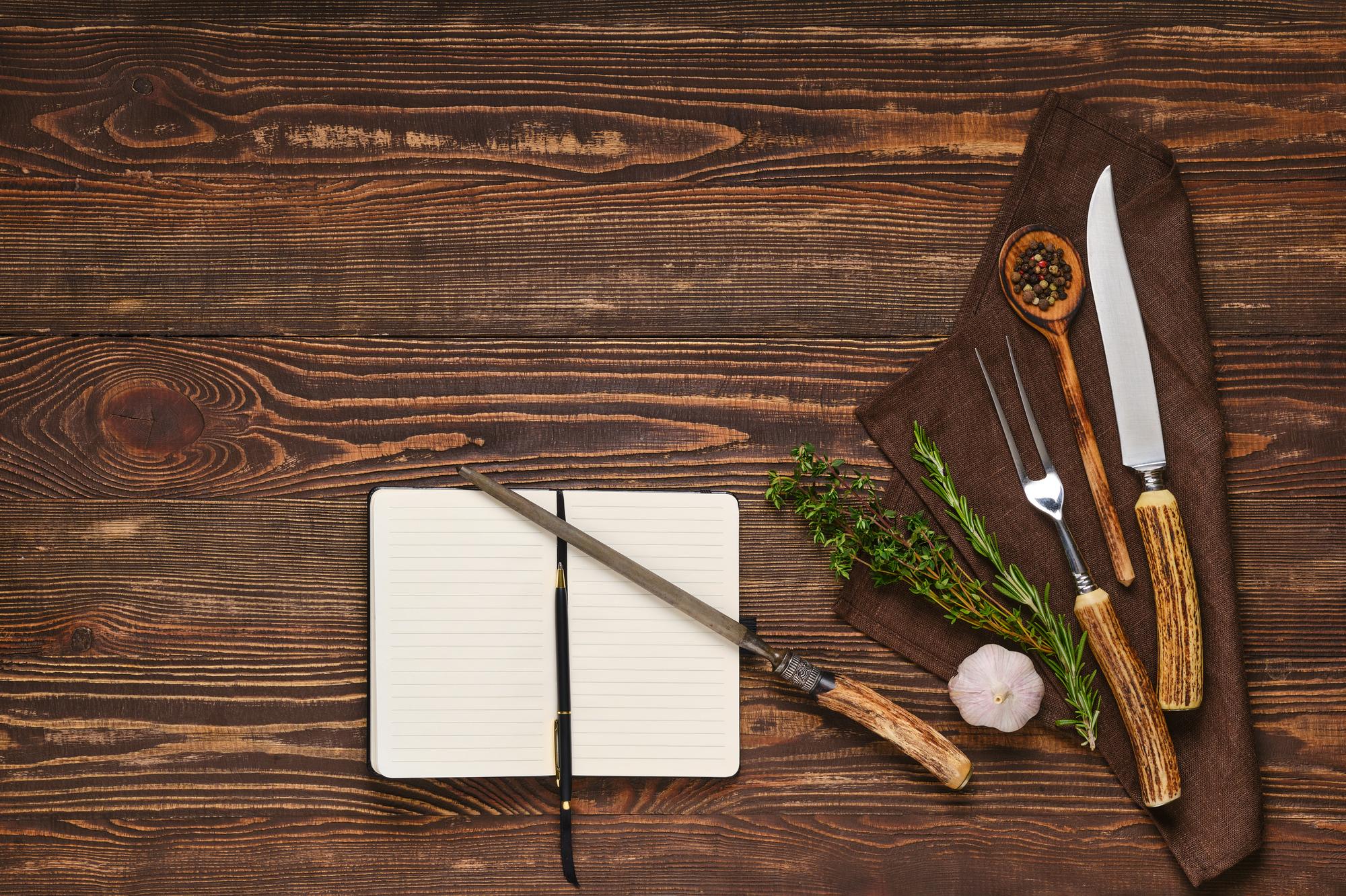 Arbeitsfläche mit Messer, Kräutern und Notizen